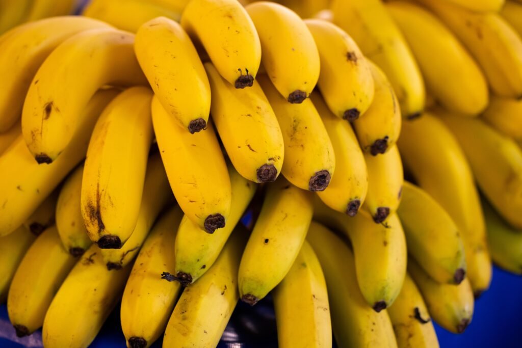 Cluster of bright yellow bananas stacked in a market, showcasing freshness and ripeness.